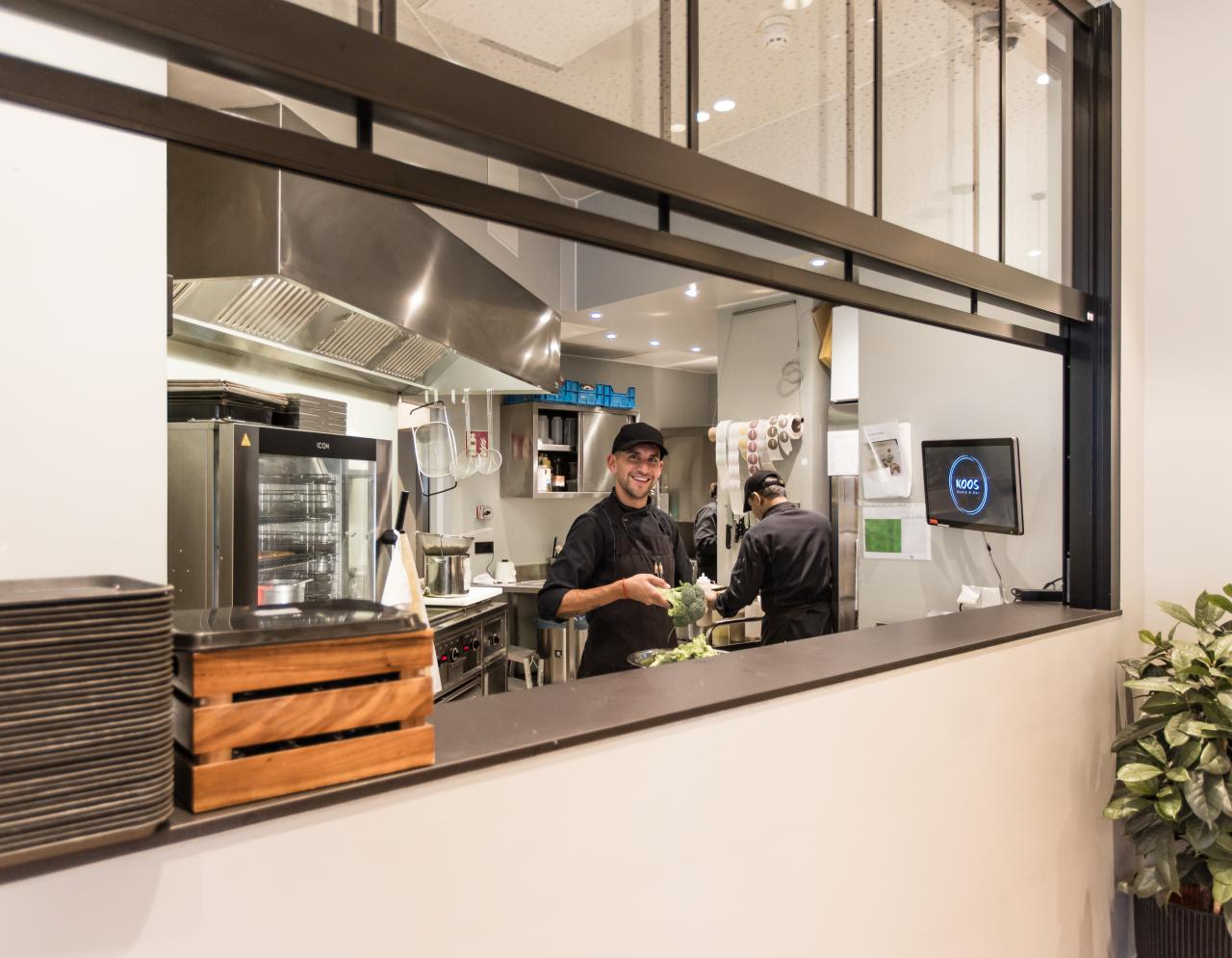 Blick in die Küche zu Koch mit Brokkoli im Koos München Change Maker Hotel