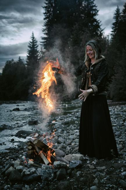 Eine blonde Frau, die an einem Lagerfeuer steht